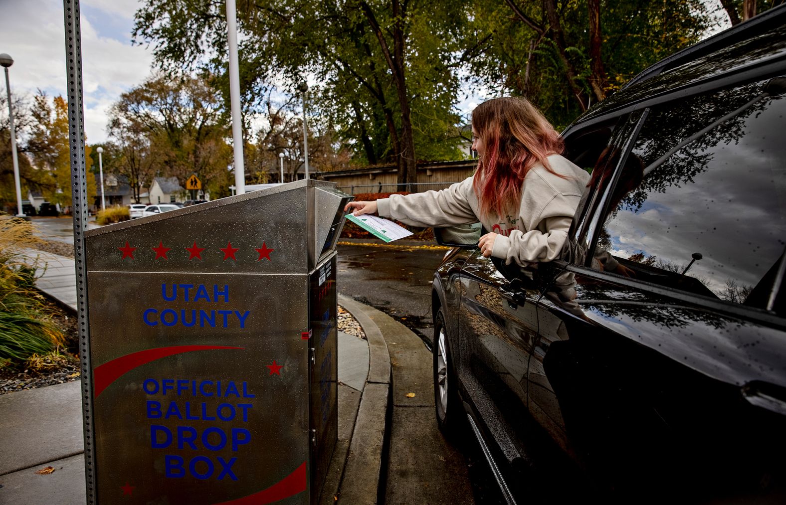 A voter drops off a ballot outside the American Fork Library in American Fork, Utah.