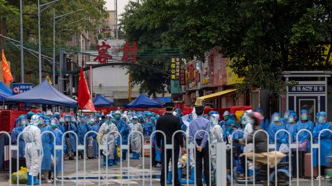 Des travailleurs en costume blanc se préparent à déplacer des résidents, portant des combinaisons de protection bleues, dans un village de Guangzhou après l'épidémie de COVID-19 le 5 novembre.