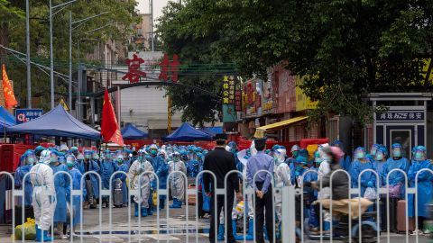 Pekerja berpakaian putih bersiap untuk memindahkan penduduk, mengenakan pakaian pelindung biru, di sebuah desa di Guangzhou setelah wabah Covid pada 5 November.