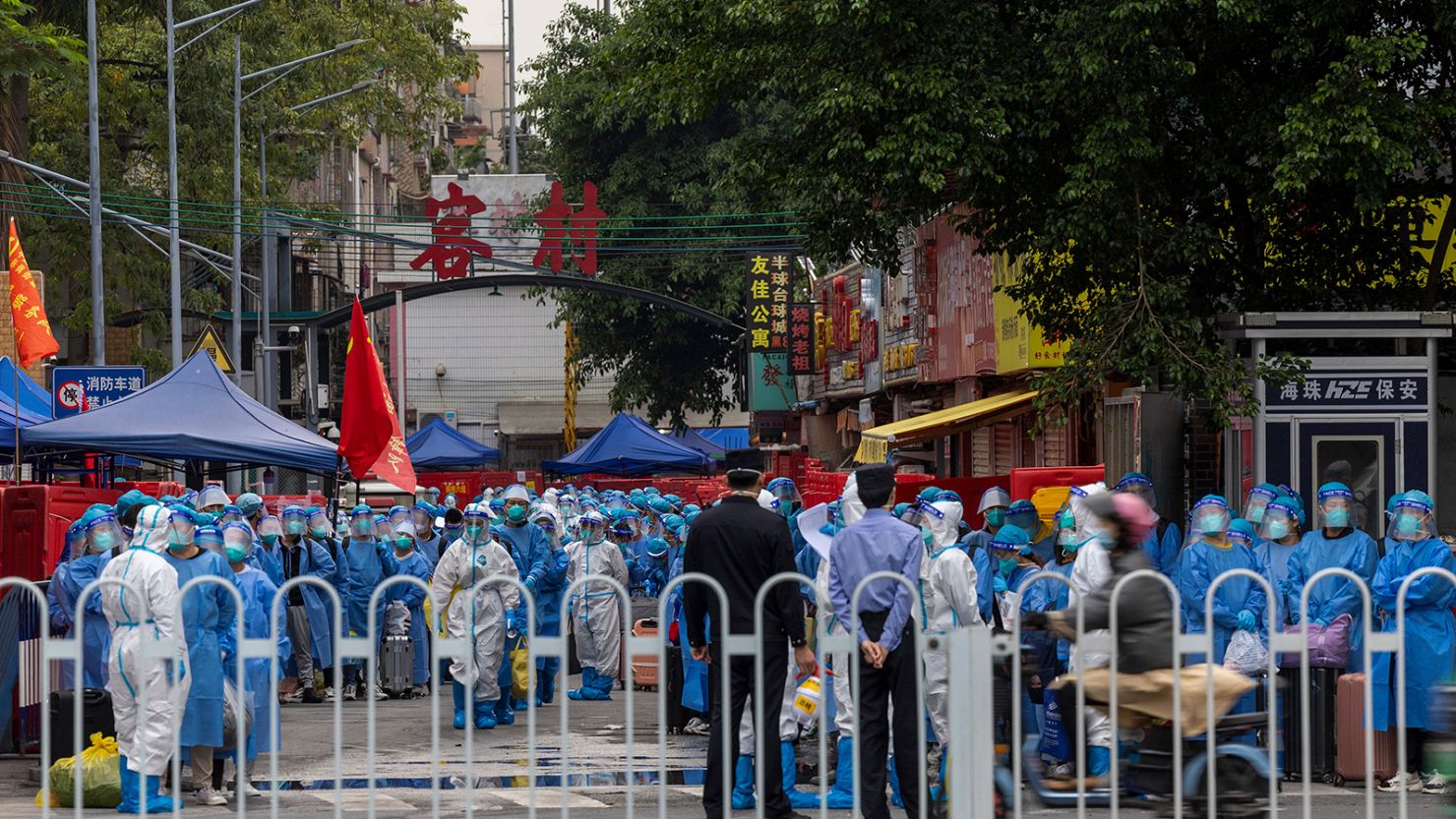 Law enforcers wearing white hazmat suits prepare to transfer residents in blue protective clothing at a high-risk neighborhood in Guangzhou on November 5.