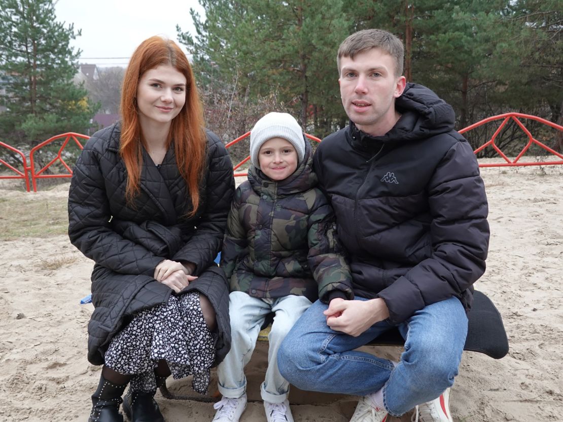 Maria Bespalaya, Ilya Kostushevich and Vladimir Bespalov sit together on a playground bench in Kyiv.