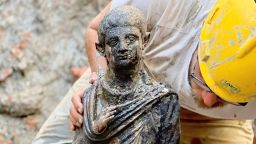 A worker holds a 2,300-year-old bronze statue which has been discovered in San Casciano dei Bagni, Italy, in this handout photo obtained by Reuters on November 8, 2022.