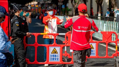 A delivery worker delivers a package to the entrance of a locked neighborhood in Liwan, Guangzhou, on Nov.