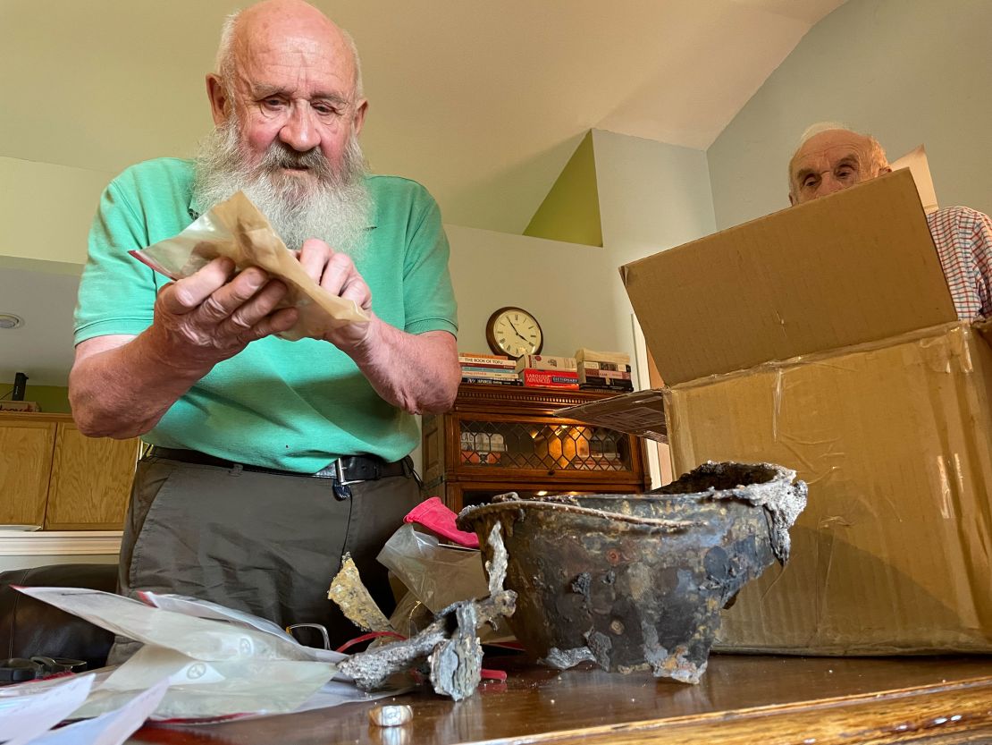 Twins David McCannel, left, and Don McCannel, right, examine items found buried with their uncle on Tarawa, including their uncle's battle helmet. 