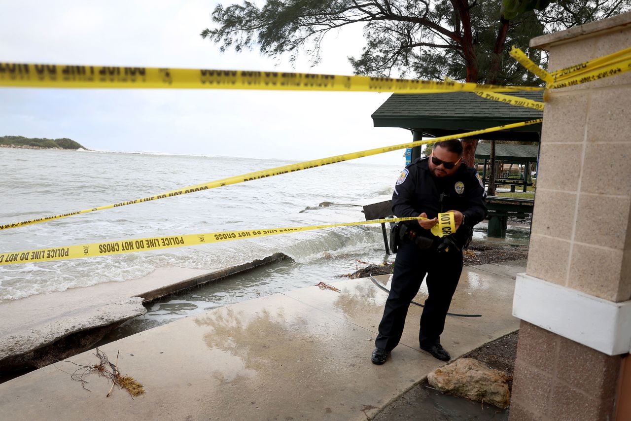 Police officer Jorge Goz puts up tape where a sidewalk was washed out in Fort Pierce, Florida, on Thursday.