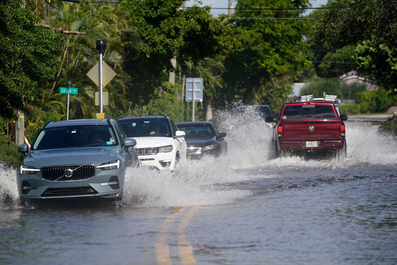 Cars make their way along a flooded road in Pompano Beach, Florida, on Thursday.
