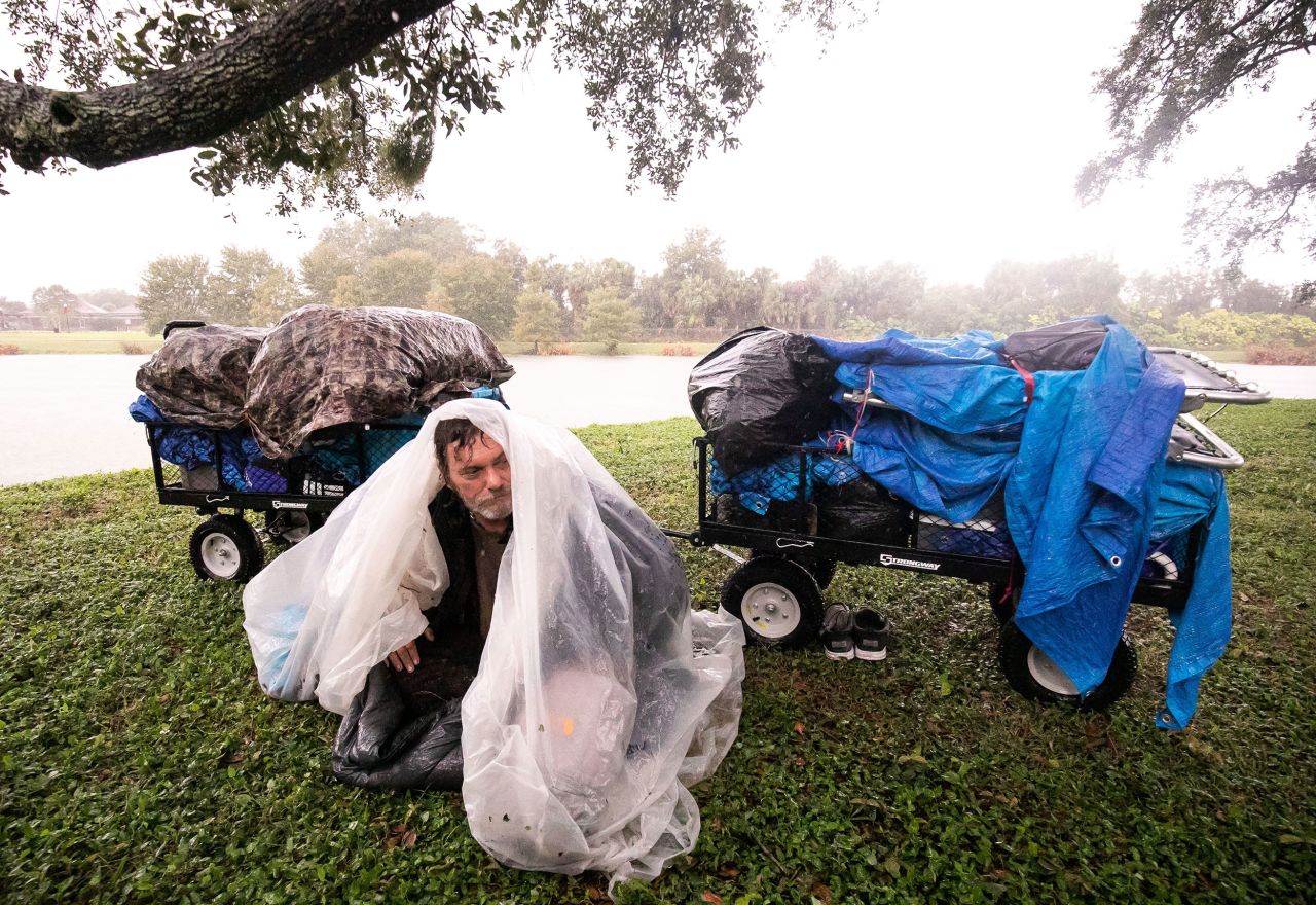 Michael Sill, who is homeless, huddles under a plastic sheet while trying to stay dry in Ocala on Thursday. He braved the storm under an oak tree because there was no where for him to stay, he said.