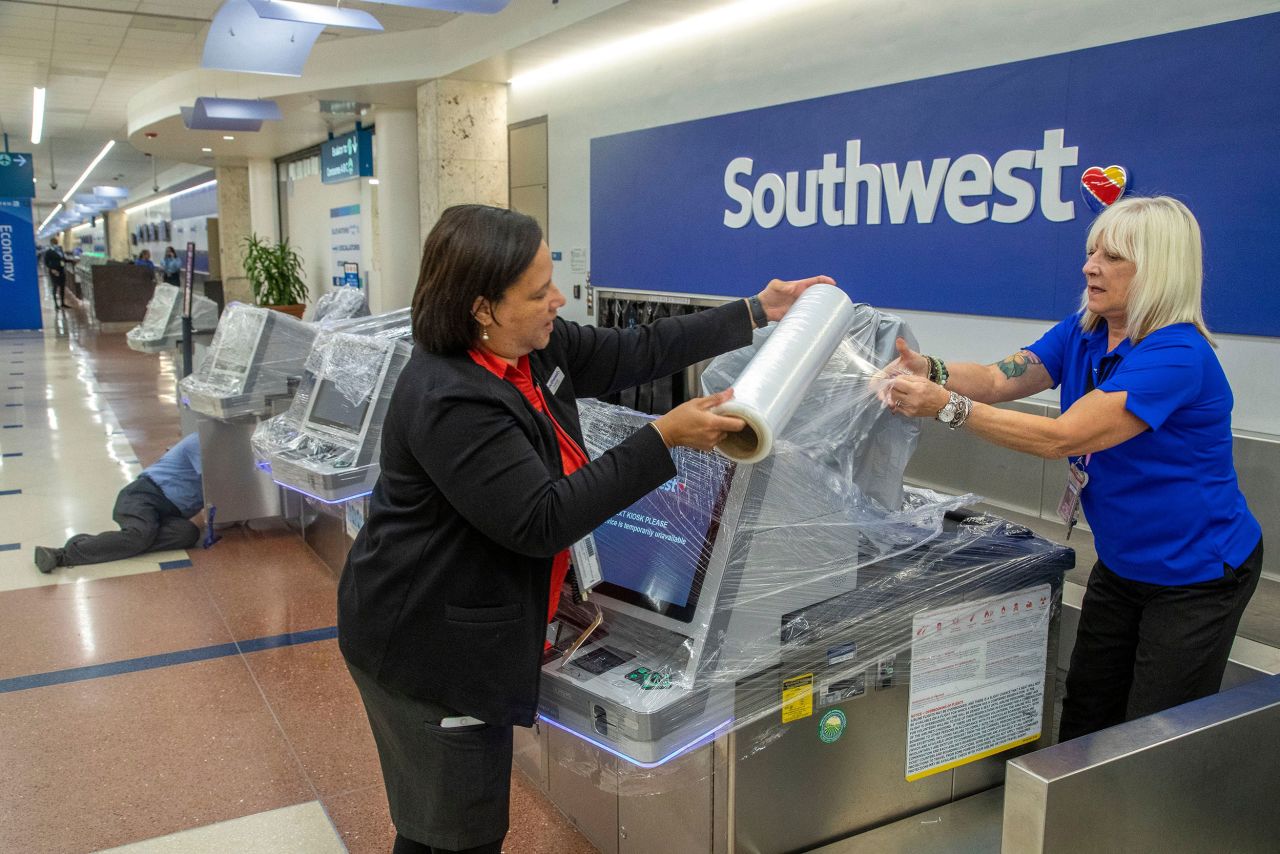 Fabiola Lindor, left, and Lisa MacNeal of Southwest Airlines cover computer systems with plastic wrap to protect them in West Palm Beach, Florida, on Wednesday.