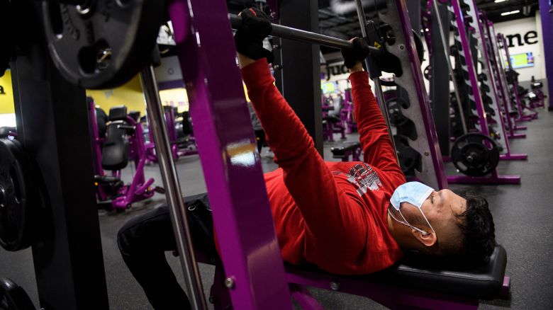A customer wears a face mask as they lift weights while working out inside a Planet Fitness Inc. gym as the location reopens after being closed due to the Covid-19 pandemic, on March 16, 2021 in Inglewood, California.
