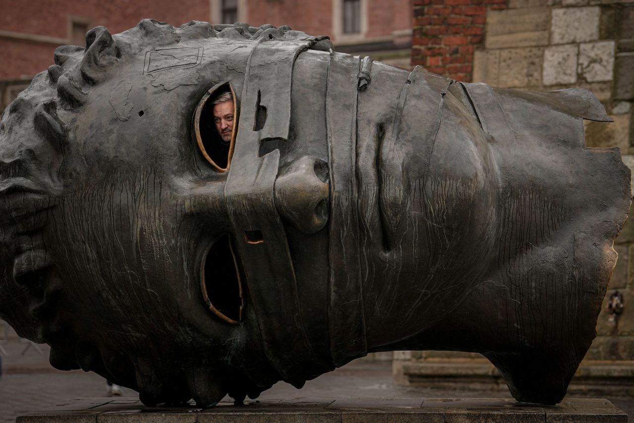 A man peers out from a depiction of Eros, the Greek god of love, in Krakow, Poland, on Thursday, November 10. "Eros Bound," by Polish sculptor Igor Mitoraj, is said to symbolize the decay of civilizations.