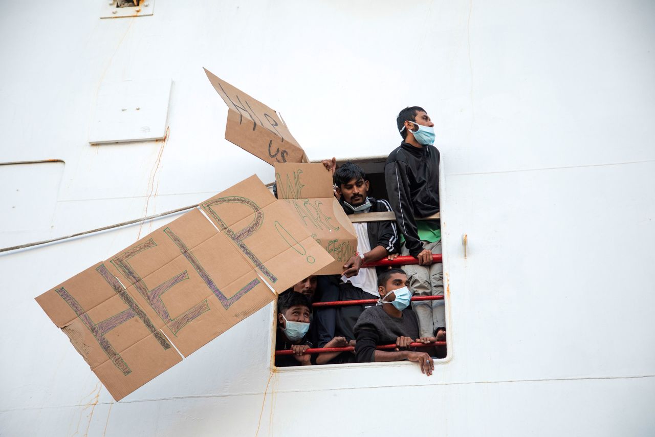 Migrants aboard the Geo Barents rescue ship hold up signs demanding their disembarkment as they wait in the port of Catania, Italy, on Tuesday, November 8. Italian authorities allowed minors and "vulnerable people" to disembark, but others had to remain at sea.