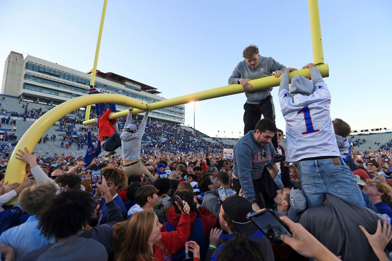 Kansas fans climb a goalpost after the school's football team defeated Oklahoma State to become bowl-eligible on Saturday, November 5.