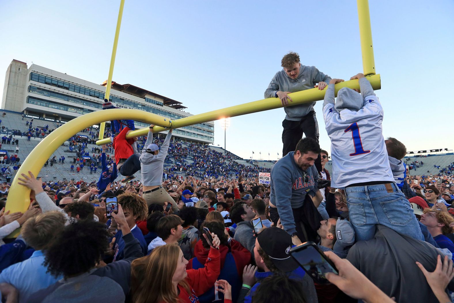 Kansas fans climb a goalpost after the school's football team defeated Oklahoma State to become bowl-eligible on Saturday, November 5.