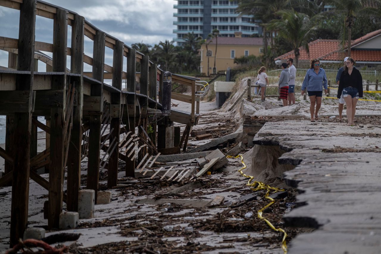 People walk by a damaged boardwalk in Vero Beach on Thursday.
