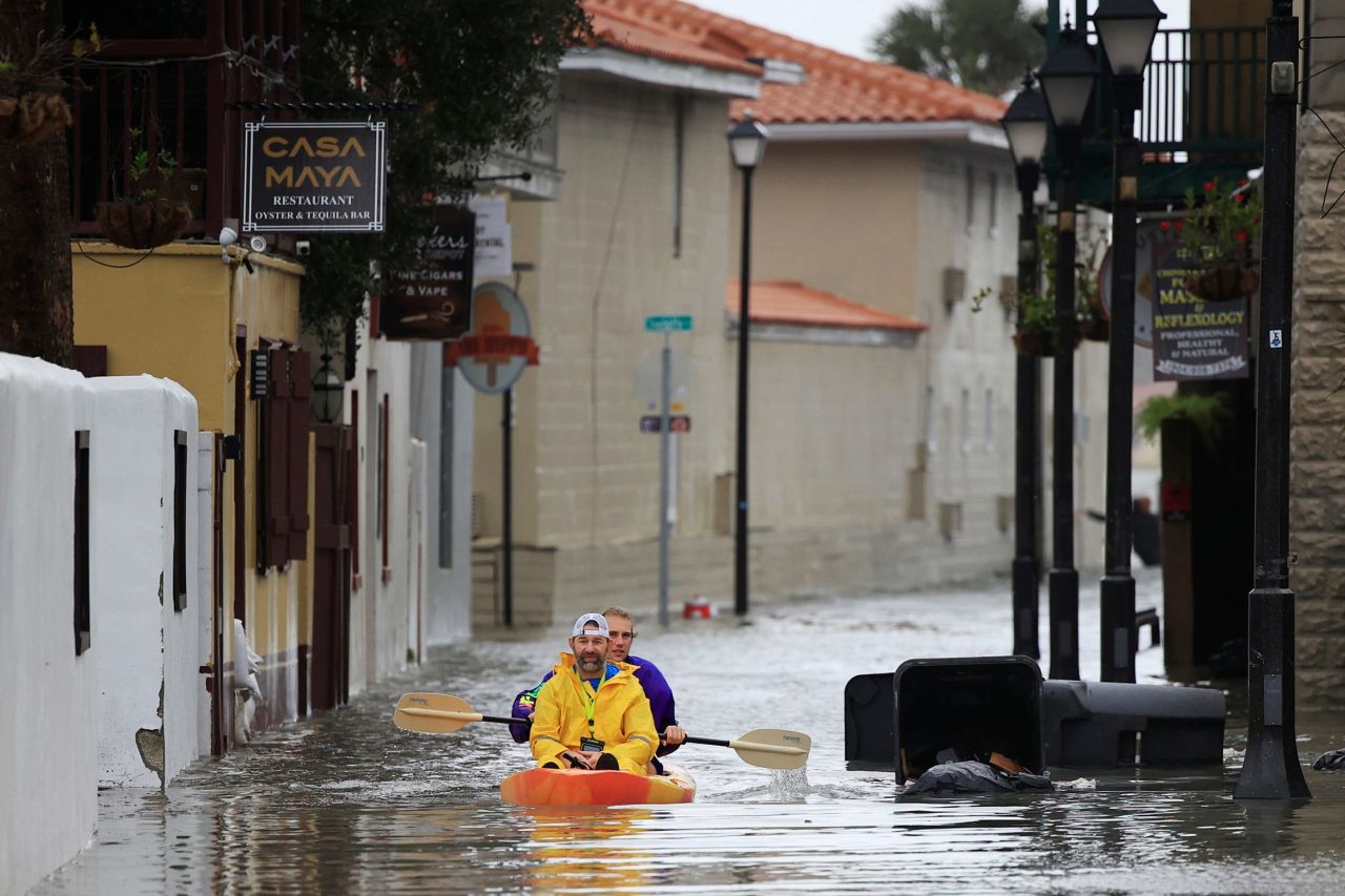 Ronnie Duvall is paddled by friend Jason Kunath through a flooded street in St. Augustine, Florida, on Thursday.