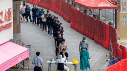 People line up to get tested in the Covid-19 screening in a apparel wholesale market enclosed by a temporary wall in Guangzhou in south China's Guangdong province Thursday, Nov. 10, 2022.  (FeatureChina via AP Images)