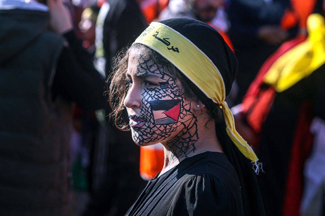 A girl with face-paint depicting the Palestinian flag looks on as others gather with flags of the Fatah movement during a rally to commemorate the 18th anniversary of the death of Palestinian leader Yasser Arafat, in Gaza City on Thursday.  