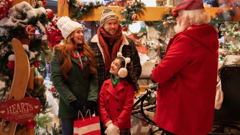Lindsay Lohan as Sierra, Chord Overstreet as Jake, Olivia Perez as Avy, and Bus Riley as a Santa-looking chestnut vendor in Netflix's "Falling For Christmas."