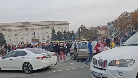 A crowd cheers and chants as they surround a car carrying Ukrainian soldiers in the Kherson suburb on Friday. 
