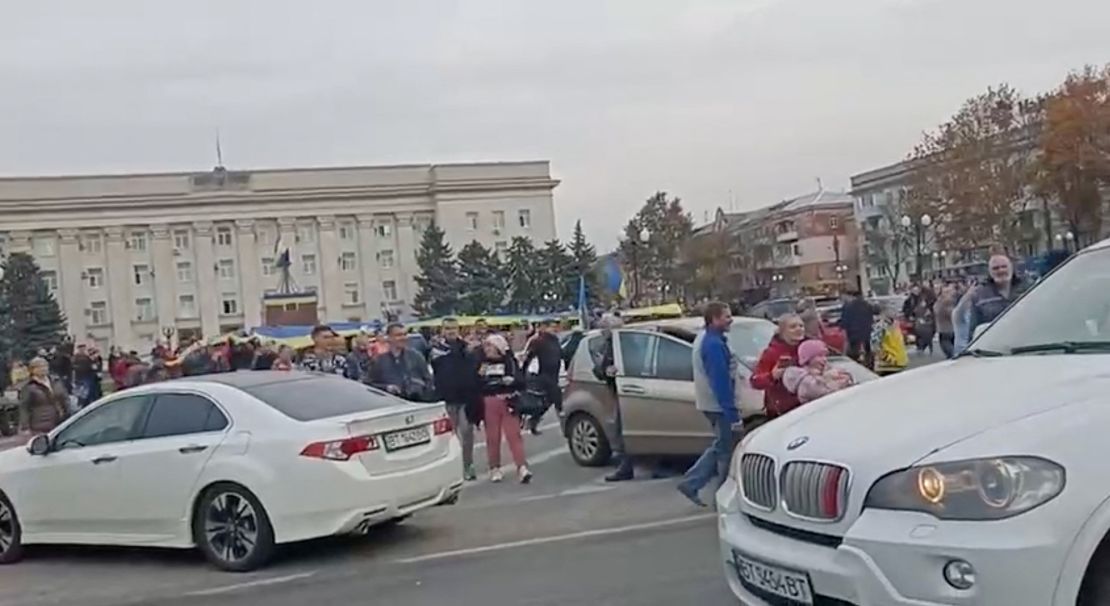 Crowd cheer and chant as they surround a car with Ukrainian soldiers in Kherson's main square on Friday. 