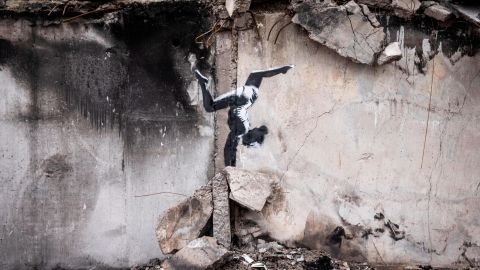 The artwork shows a female gymnast balancing on a pile of rubble on the side of a building damaged by Russian strikes in Borodianka. 