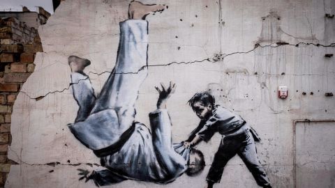 A mural not officially claimed by Banksy shows a man being flipped during a judo match with a boy. 