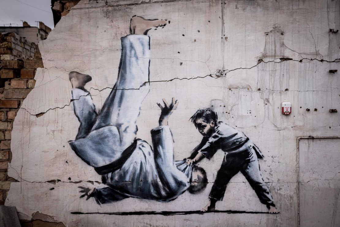 A mural shows a man being flipped during a martial arts match with a young boy. 