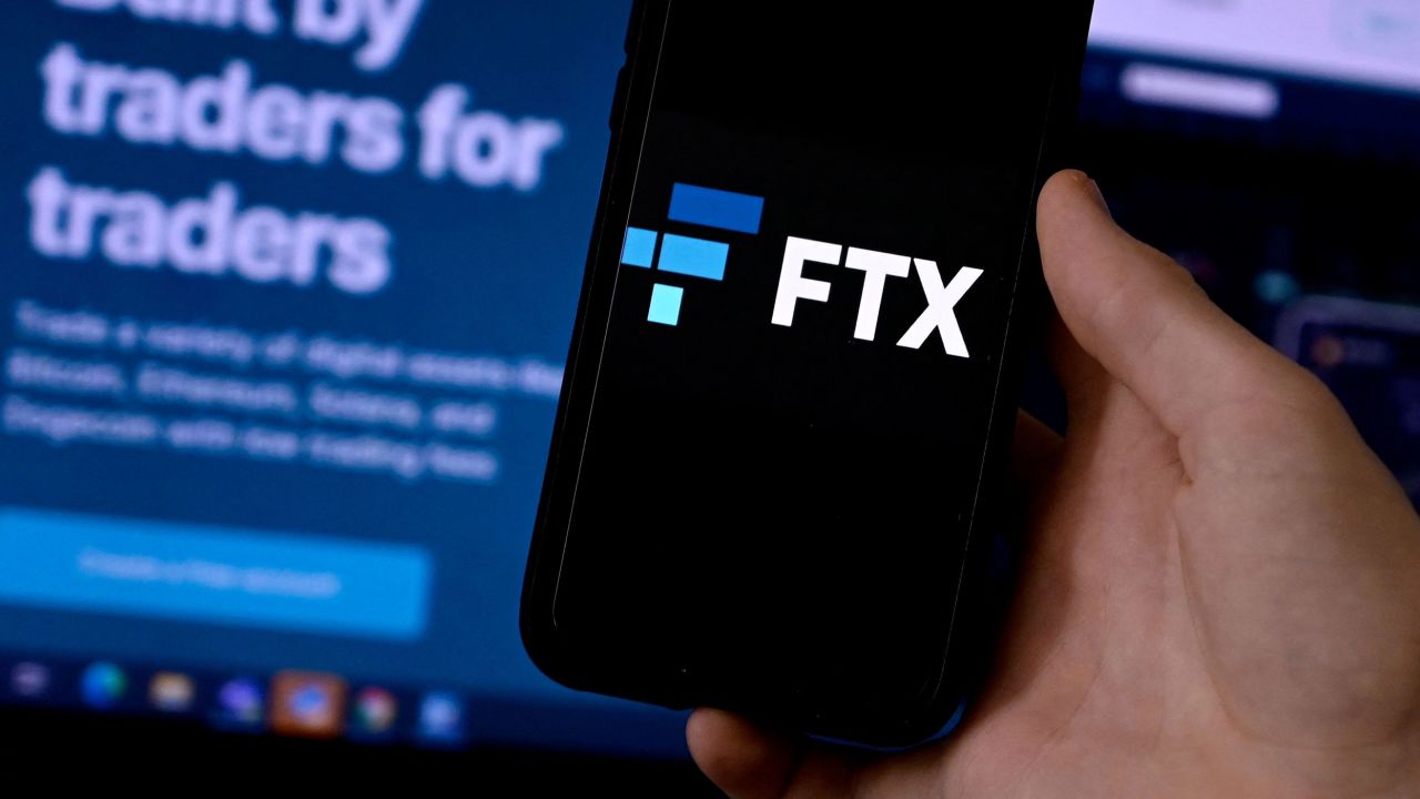 This illustration photo shows a smart phone screen displaying the logo of FTX, the crypto exchange platform, with a screen showing the FTX website in the background in Arlington, Virginia on February 10, 2022.