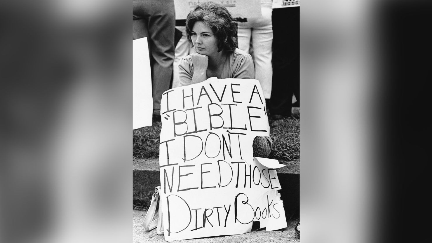 Woman protesting "those dirty books" sits stoically on a curb in Charleston, West Virginia, in 1974. Schools were firebombed and school buses fired at in the controversy. 