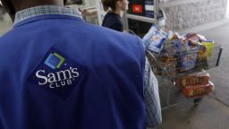In this Sept. 9, 2010 file photo, a store associate watches as a customer leaves with her purchases at Sam's Club in Jackson, Miss.