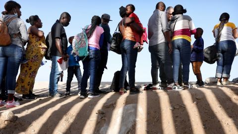 Immigrants from Haiti, who crossed through a gap in the US-Mexico border barrier, wait to be processed by the U.S. Border Patrol on May 20, 2022, in Yuma, Arizona.