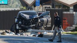 An investigator walks past a mangled SUV that struck Los Angeles County sheriff's recruits in Whittier, Calif., Wednesday, Nov. 16, 2022. The vehicle struck several Los Angeles County sheriff's recruits on a training run around dawn Wednesday, some were critically injured, authorities said. (AP Photo/Jae C. Hong)
