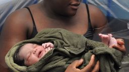 mother in birthing tub examines newborn's feet