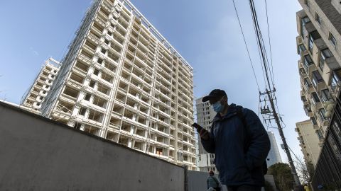 A pedestrian walks past unfinished buildings at the West Bund Park residential project in Shanghai, China, January 14, 2022.