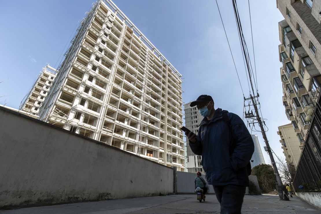 A pedestrian passes unfinished apartment buildings at the West Bund Park residential project in Shanghai, China, on Jan. 14, 2022.