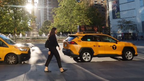  A woman walks past two taxi cabs in Columbus Circle as the sun rises on October 27, 2022, in New York City. 