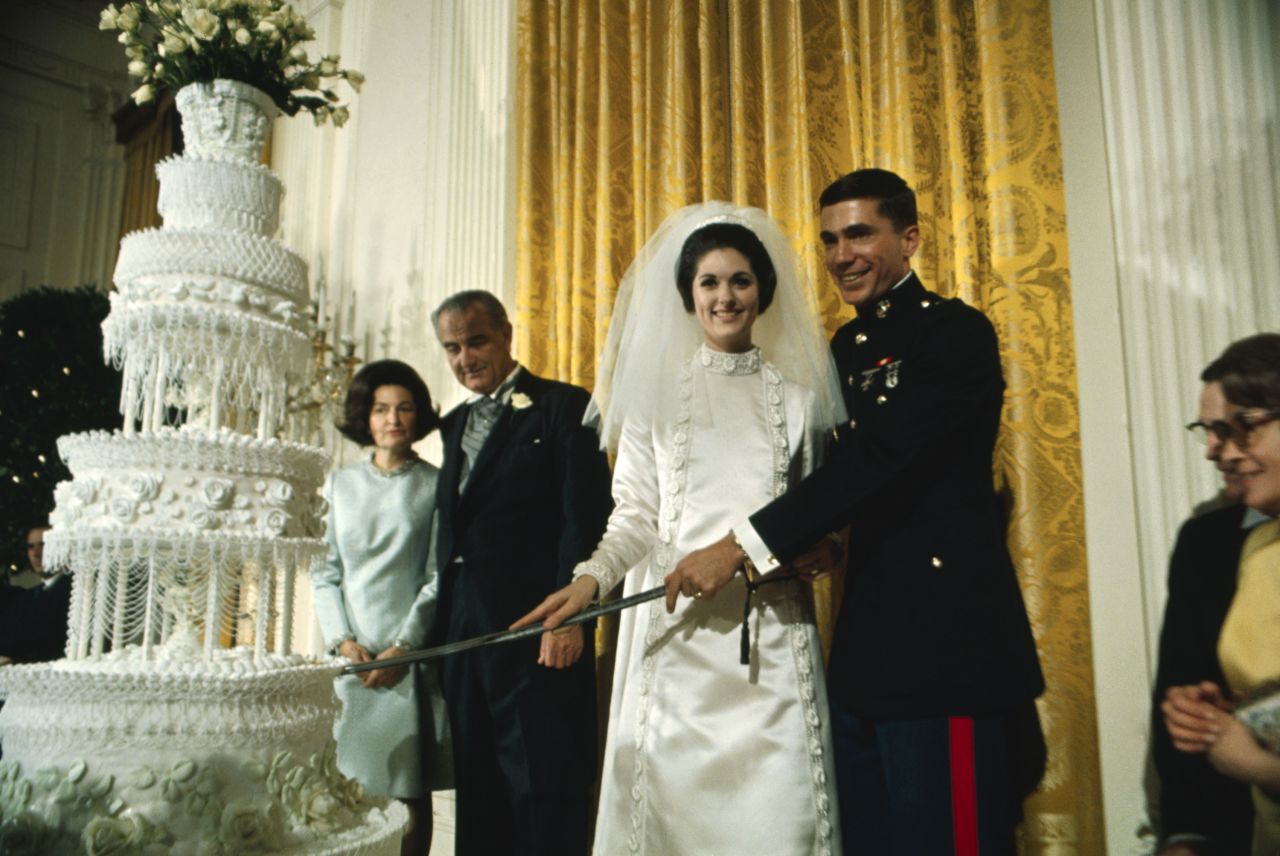 Lynda Bird Johnson, daughter of President Lyndon Johnson, cuts a piece of cake during her wedding to Chuck Robb in 1967.
