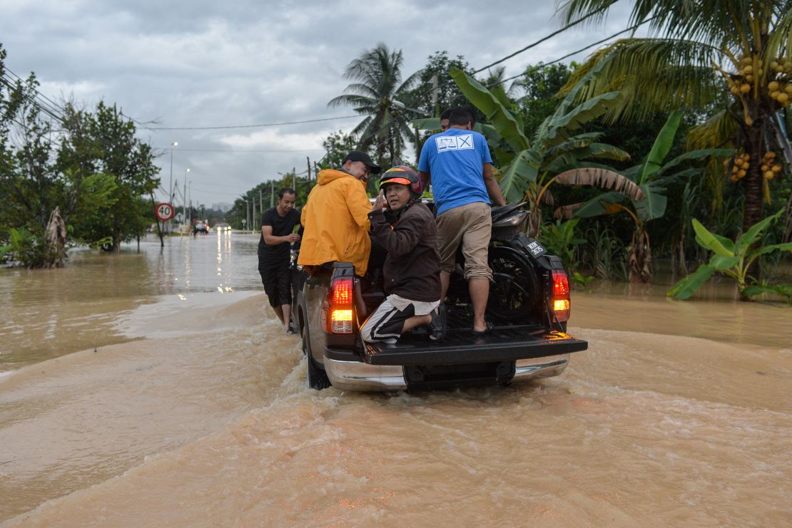 People rescue a motorcycle in a flooded street in Klang, Malaysia on November 10, 2022.