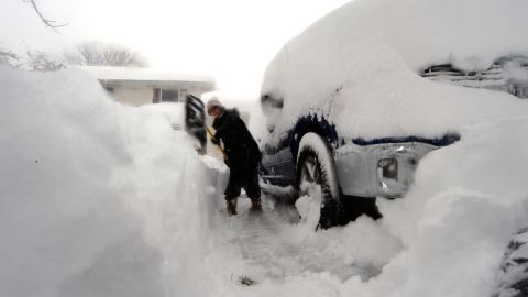 Heather Ahmed utilise une pelle pour creuser un chemin à côté d'un véhicule après qu'une forte tempête de neige à effet de lac a frappé Hambourg, New York, vendredi. 