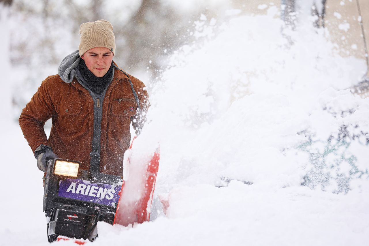 A man uses a snowblower to dig out a vehicle on Friday.