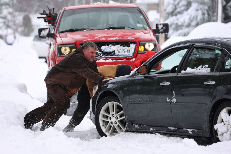 Residents push a stuck vehicle in Buffalo on Friday.