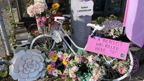 A memorial has been set up at the site of Sarah's crash, featuring a white bicycle embedded with flowers.
