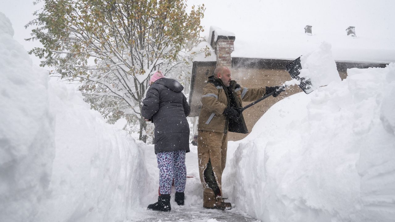 Jenny Vega (L) and Roberto Rentas shovel snow in front of their house in Buffalo Friday.