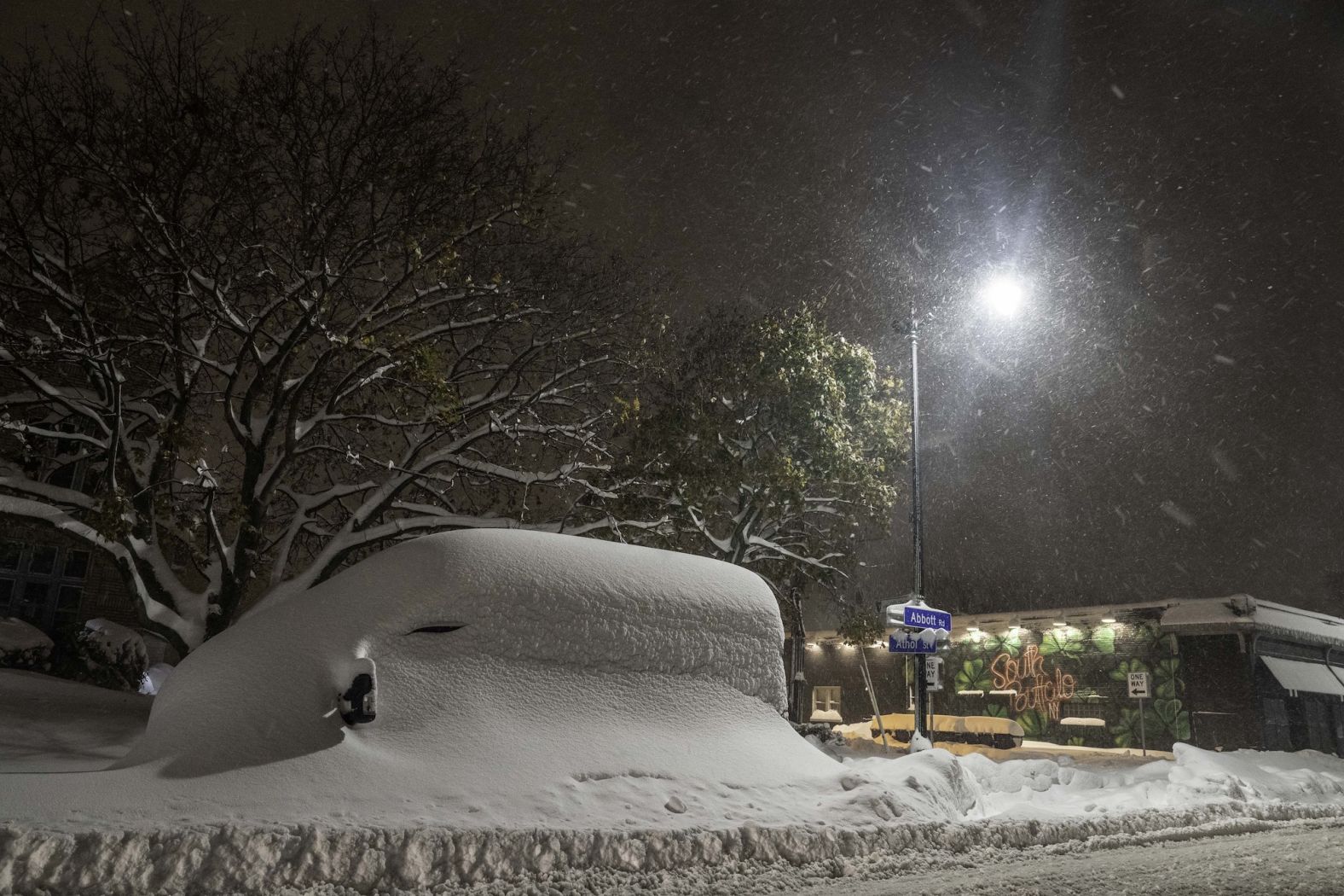 A van is seen buried under snow at night in Buffalo on Friday, November 18.