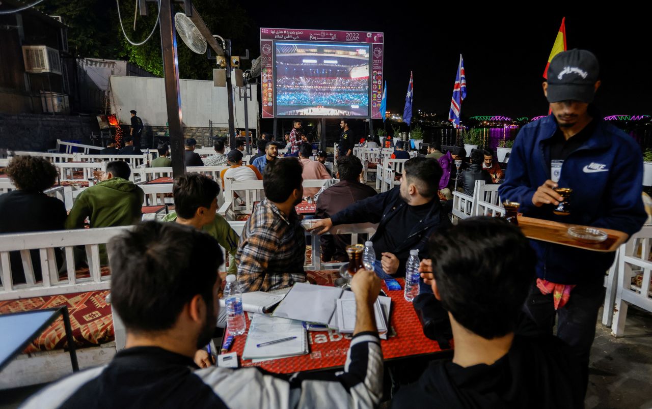 People watch the opening ceremony from a cafe in Baghdad, Iraq.