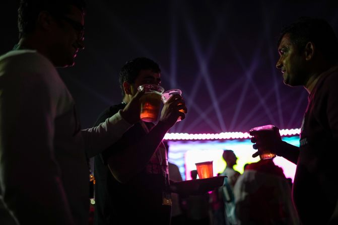 Fans drink beer as they watch the match from a fan zone in Doha. <a href="index.php?page=&url=https%3A%2F%2Fwww.cnn.com%2F2022%2F11%2F18%2Ffootball%2Fqatar-world-cup-beer-stadium-spt-intl%2Findex.html" target="_blank">No alcohol is being sold</a> inside the stadiums during the World Cup. Qatar tightly regulates alcohol sales and usage.