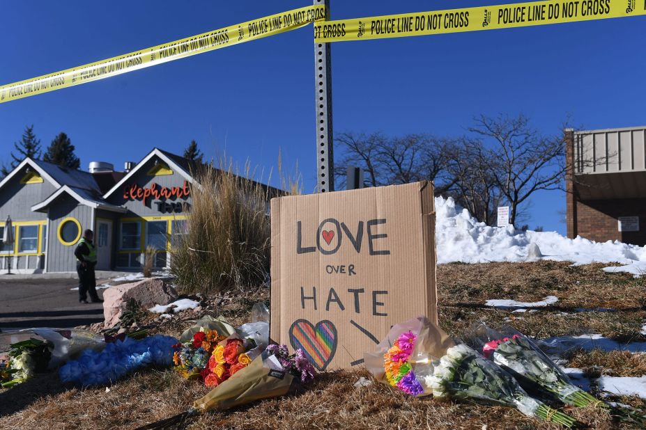 Bouquets of flowers and a sign reading "love over hate" are left near Club Q on Sunday.