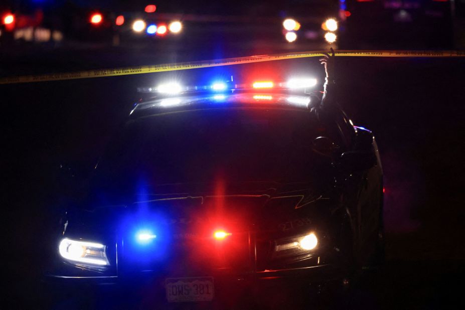 A police officer lifts barricade tape as authorities respond to the scene of the mass shooting.