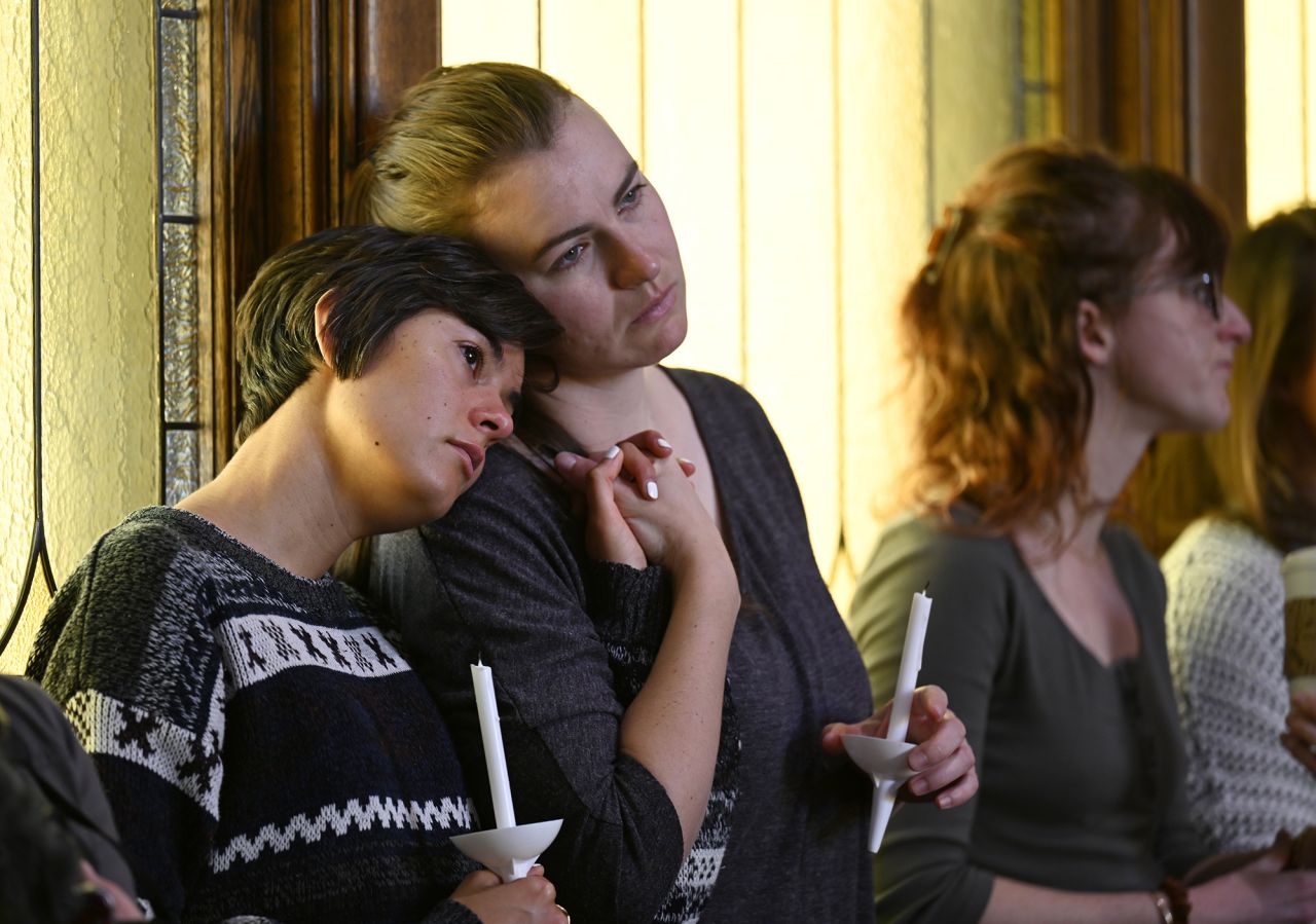Sophia Diana, left, holds her friend Lex Chapman's hand during the vigil at the All Souls Unitarian Church.