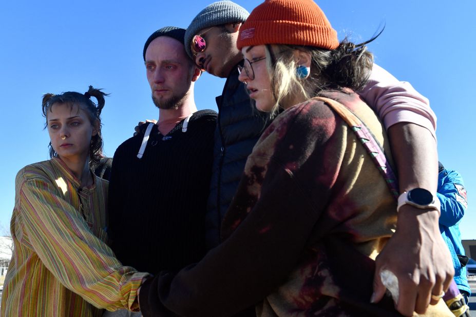 Paige H., Tyler Johnston, Keenan Mestas-Holmes and Altas Pretzeus embrace while paying their respects at a memorial in Colorado Springs on Sunday.